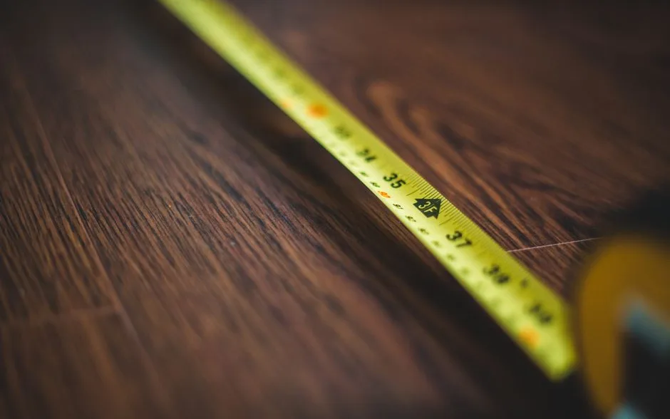 Mètre ruban déroulé sur le sol d’une pièce pour relever les dimensions du logement